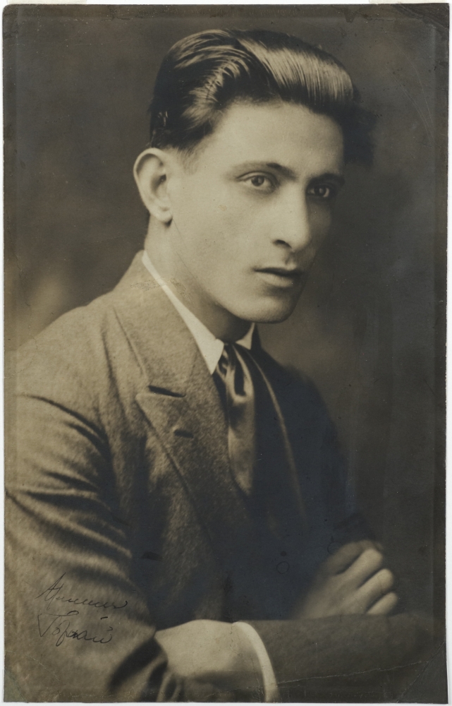 Professional portrait of a three-quarter view of a young man in a wool suit with his arms crossed