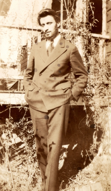 Standing man in a double breasted suit with his hands in his pockets posing in a yard